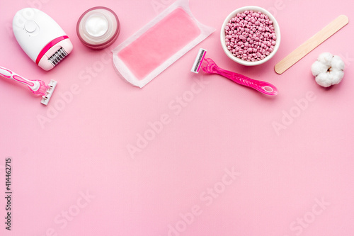 Cosmetics and means for epilation with flowers on pink background, flat lay