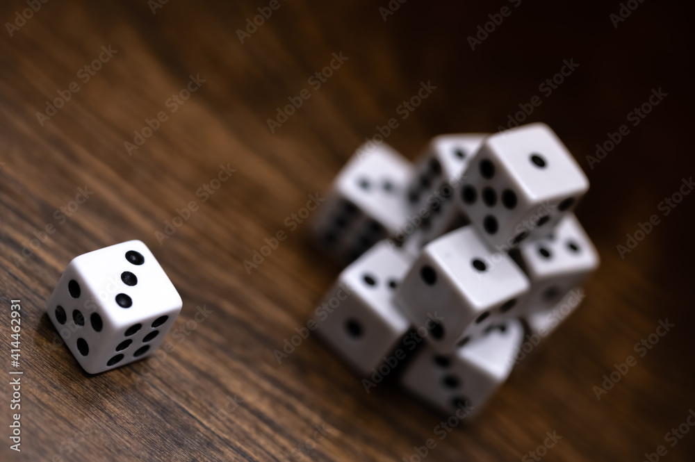 top view of dice on wood table showing a three with a stack of dice in the background top view of dice on wood table showing a three with a stack of dice in the background
