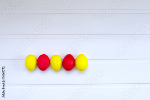 yellow and red Easter eggs row in the lower left corner, spring and Easter card, top view, space for text