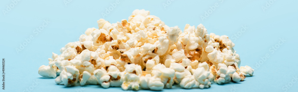 pile of tasty salty popcorn on blue, banner, cinema concept