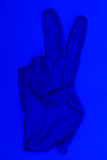 blue medical glove on a blue background two fingers protruding