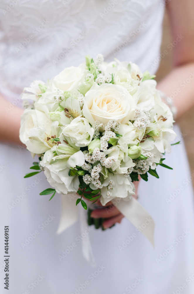 The bride holds a bouquet of flowers in her hands at the wedding, ceremony. Close-up. The bride holds a bouquet of flowers in her hands at the wedding, ceremony. Close-up.