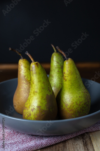 Four 4 green pears on a blue plate