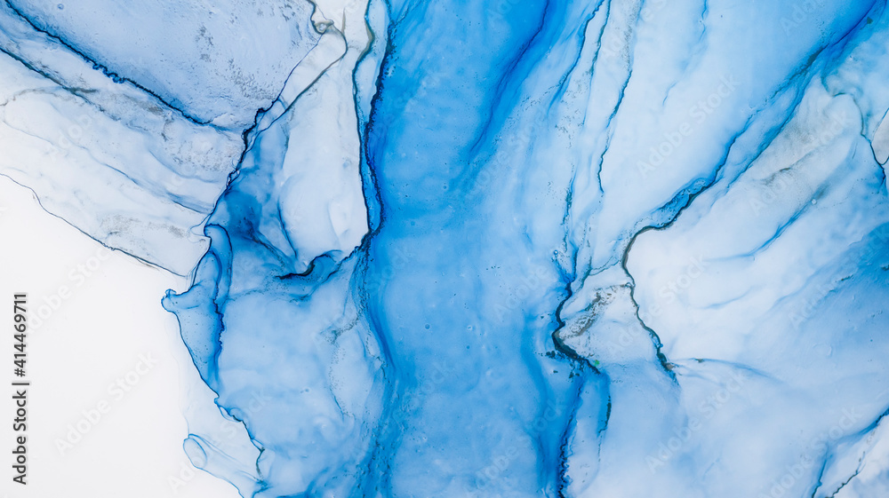 Naklejka premium Blue alcohol stains of paint with the addition of gold powder. Subtle waves of paint, abstract blue waves of the ocean, lines of marble. Liquid paints, gradient stains, painting.
