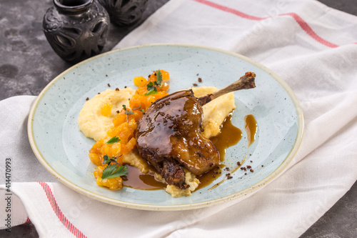 Duck confit Roasted duck leg with puree on blue plate on the table