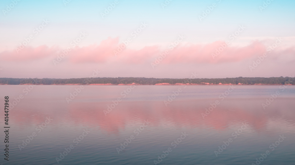 Panoramic reflection of pink clouds on a foggy morning at Saylorville Lake, Iowa. Blue hour, cotton candy clouds, sunrise in the Midwest, USA. 