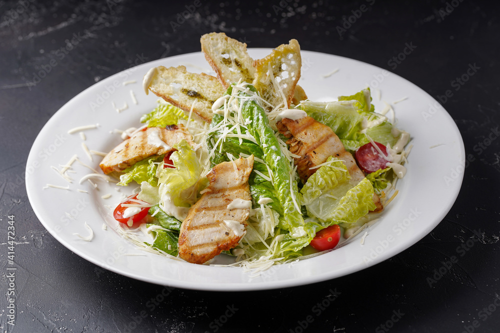 Caesar salad with chicken on a dark background. Caesar salad with chicken on a dark background.