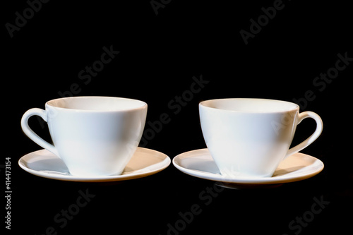pair of white ceramic cups on a black background