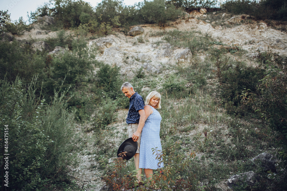 Elderly couple resting in nature and holds hands together