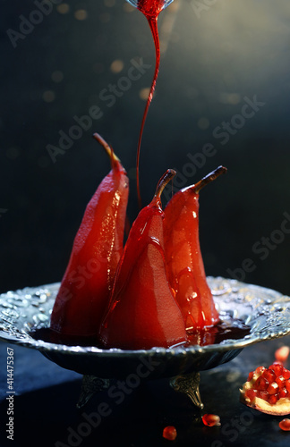 Poached pear in red wine on a black background