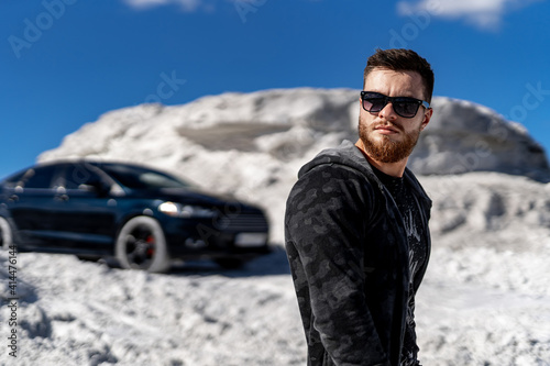 Cool man. Beautiful model outdoors, city style fashion. A handsome man model walking to luxury car. Young trendy man in modern clothing. © Vadim