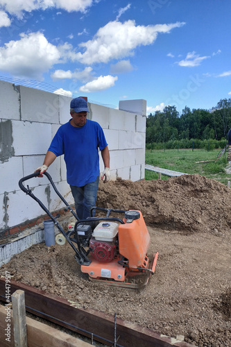 Construction work on the construction site, soil compaction with a vibrating plate, manual equipment.