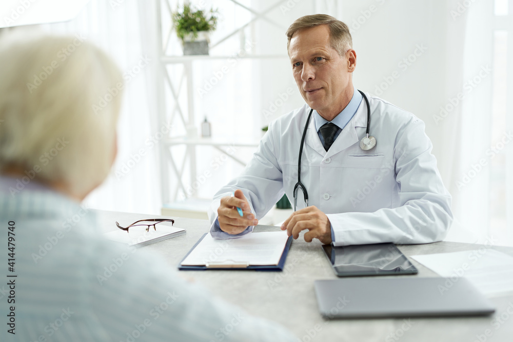 Handsome male doctor having appointment with patient in clinic