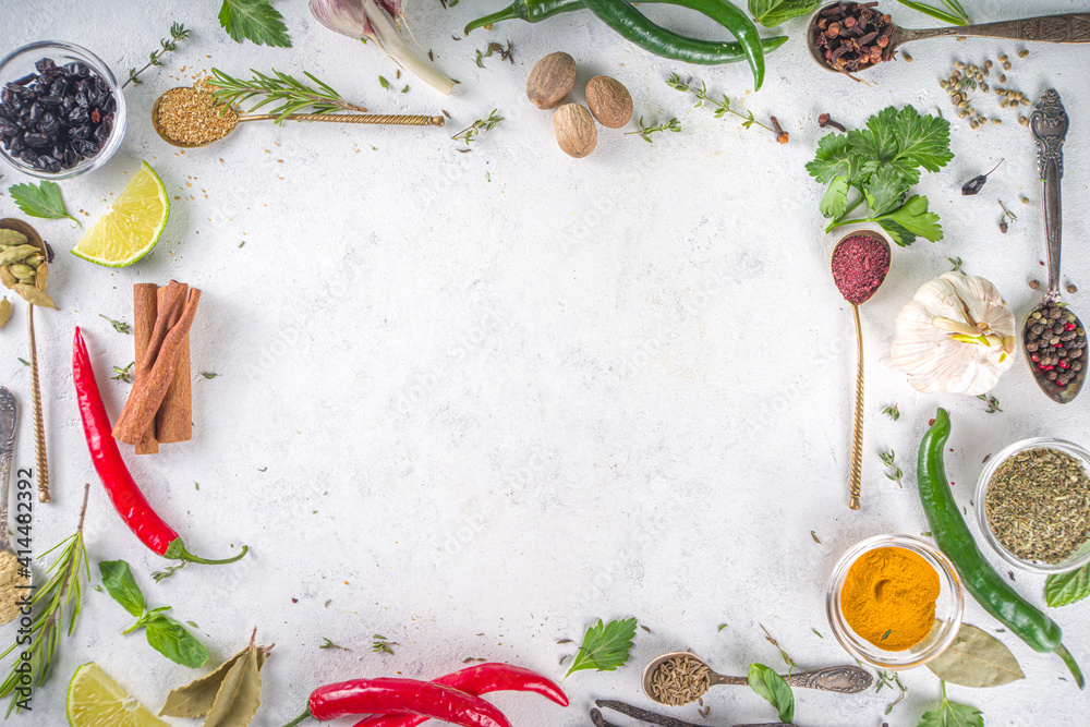 Fresh herbs, dried colorful spices. Cooking background flatlay with variety spices, herbs pepper, vanilla bean, cinnamon, basil, rosemary, chilli red green peppers, mint, parsley White table top view