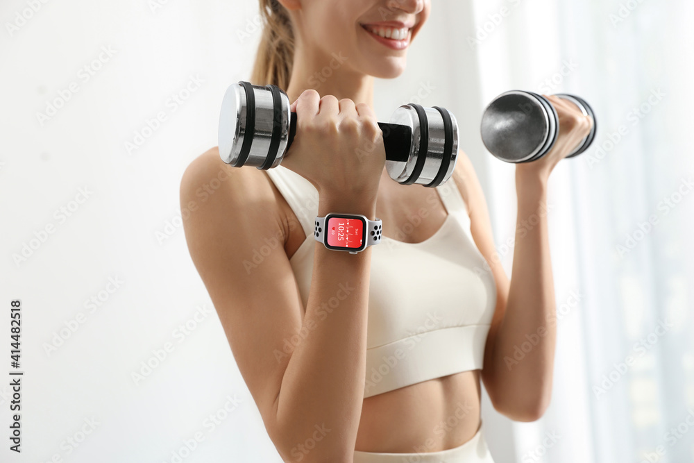 Young woman wearing smart watch during training indoors, closeup Young woman wearing smart watch during training indoors, closeup