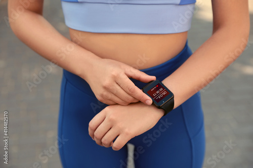 Woman using stylish smart watch during training outdoors, closeup