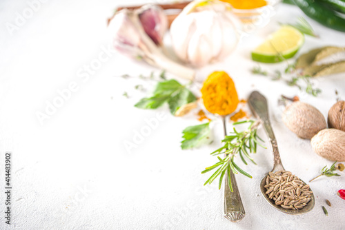 Fresh herbs, dried colorful spices. Cooking background flatlay with variety spices, herbs pepper, vanilla bean, cinnamon, basil, rosemary, chilli red green peppers, mint, parsley White table top view