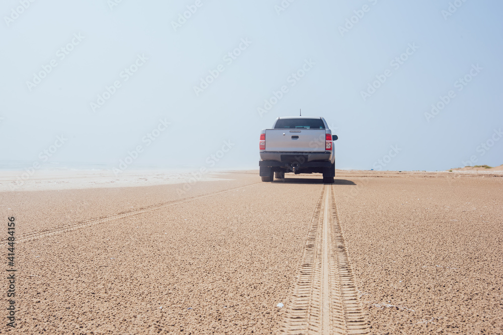 Car driving on sandy coast near ocean