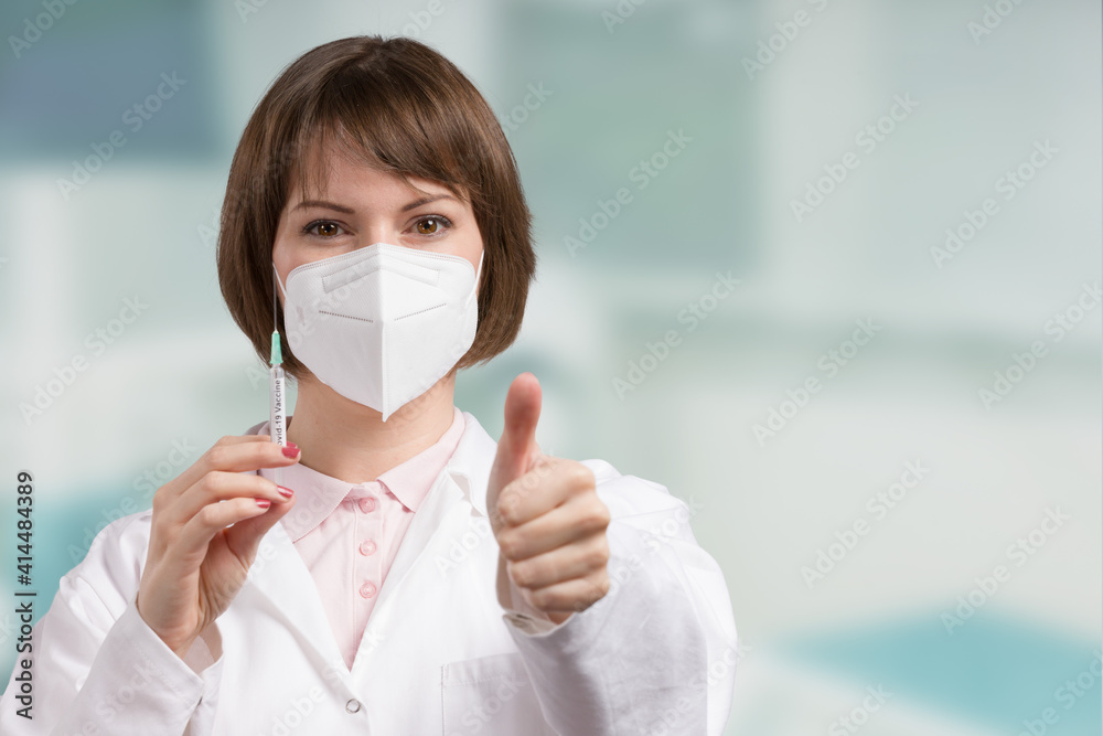 female doctor or nurse with syringe pulled up with a vaccination serum shows thumbs up female doctor or nurse with syringe pulled up with a vaccination serum shows thumbs up