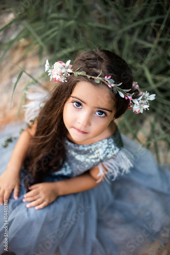 Summertime vacations in thailand. Beautiful little girl with wreath and in dress looks at camera posing in calming seacoast.