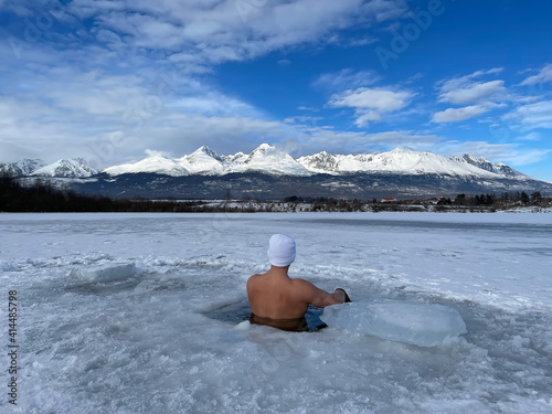 hardy man in ice water with snow with white cap