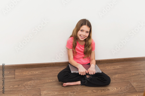 Young girl sitting at home on the floor and work with laptop. Technology, communication and education concept.