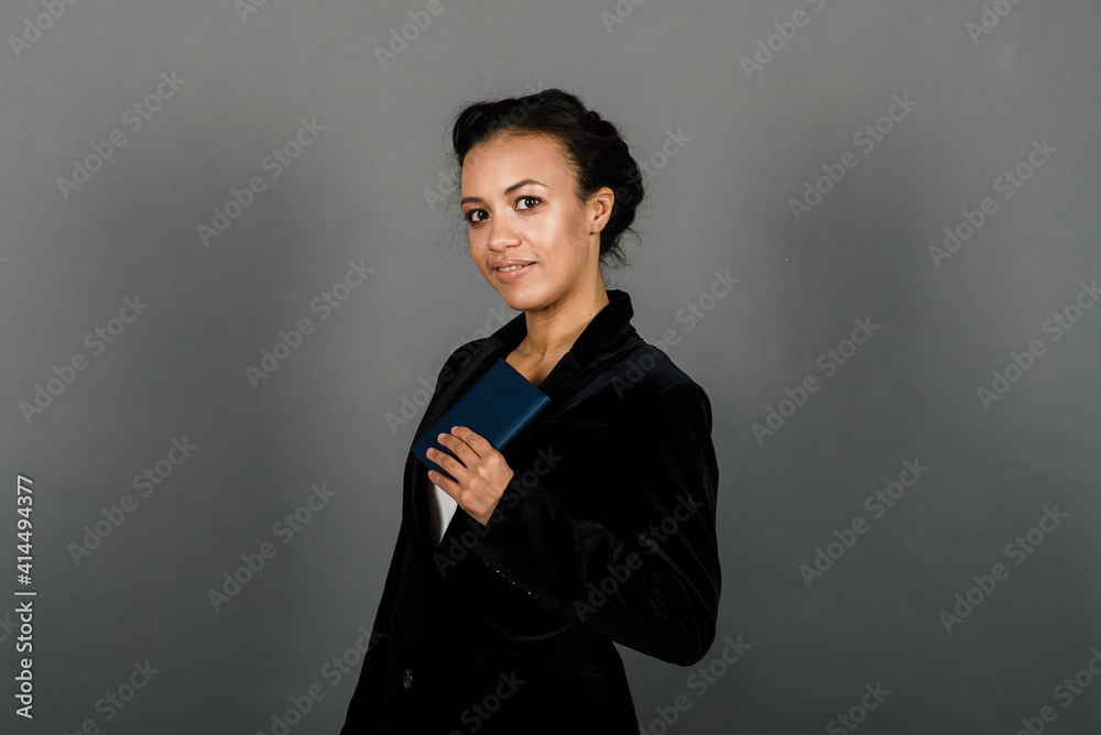 Successful young business woman with hands folded smiling over grey background