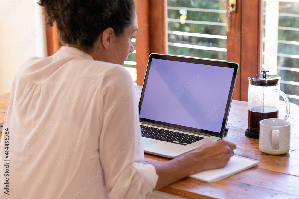 Caucasian woman using laptop working from home, making notes Caucasian woman using laptop working from home, making notes