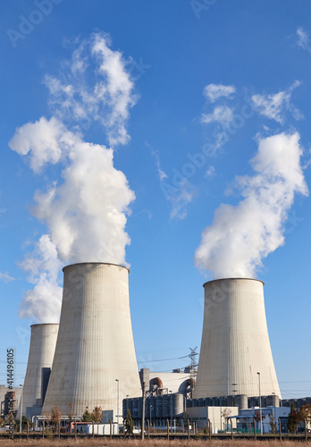 Power plant with smoking chimneys against blue sky.