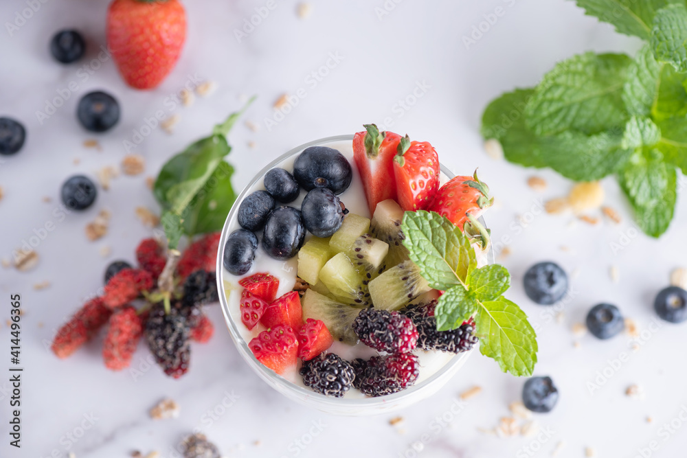 Homemade muesli, bowl of oat granola with yogurt, fresh blueberries, mulberry, strawberries, kiwi, mint and nuts board for healthy breakfast, copy space. Healthy breakfast concept. Clean eating. Homemade muesli, bowl of oat granola with yogurt, fresh blueberries, mulberry, strawberries, kiwi, mint and nuts board for healthy breakfast, copy space. Healthy breakfast concept. Clean eating.