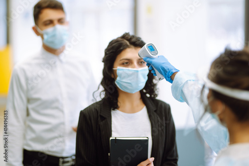 Temperature screening office workers. Disease control expert in visor and protective gloves with an Infrared thermometer equipment to check the temperature at office during pandemic in quarantine. 