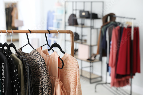 Different stylish clothes on rack in dressing room, closeup