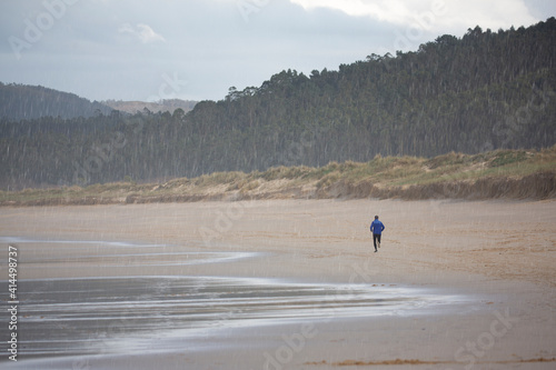 Corredor entrena corriendo por la playa de buena ma  ana en un d  a soleado frente al mar.