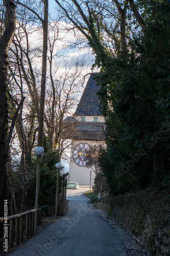 Blick auf den Grazer Uhrturm durch eine Allee