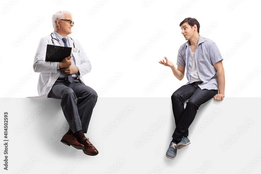 Young man sitting on a blank panel and talking to a mature male doctor Young man sitting on a blank panel and talking to a mature male doctor