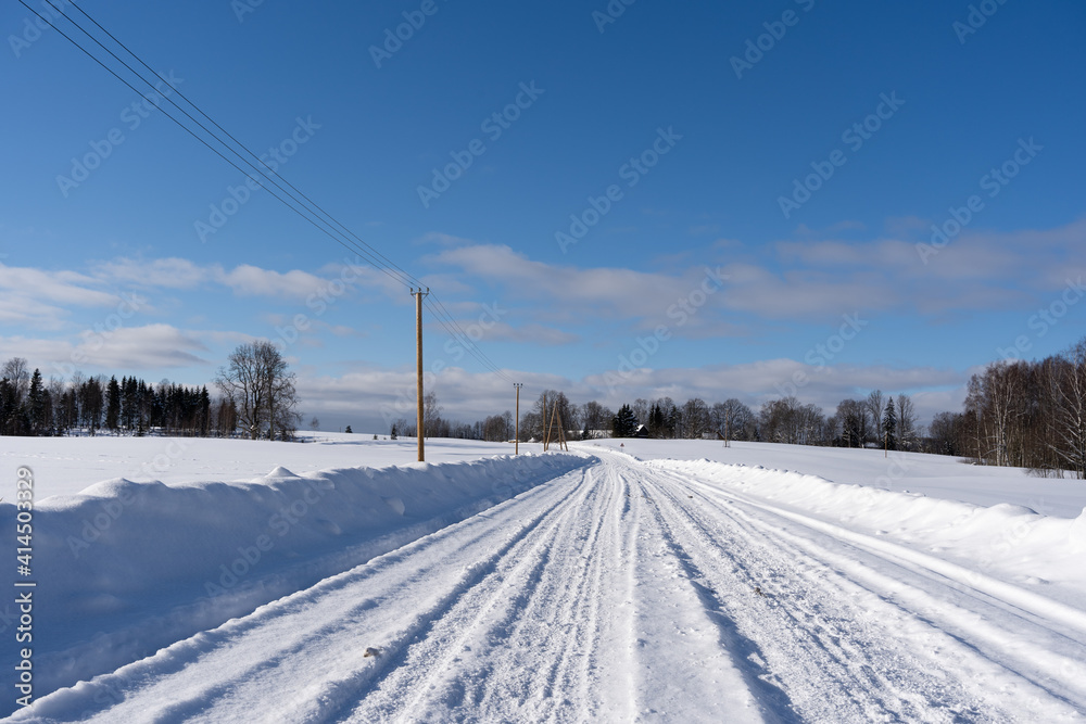 Fototapeta premium road in the middle of the field that is covered with snow