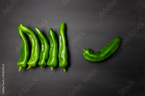 A lot of green peppers on dark, black background in horizontal line. Colorful Vegetables, ingredients for cooking