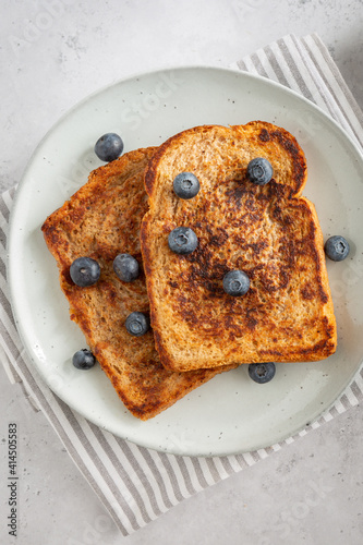 Close-up from above of two slices of french toast with blueberries on a plate on grey background, fresh clean style