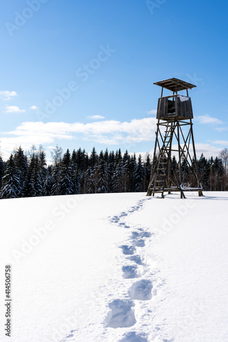 white fluffy snow and on it stands a large hunting tower built of wood