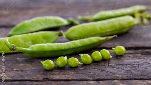 Green pea pods and peas on a wooden background