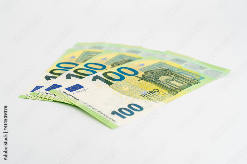 Green new one hundred Euro banknotes on a white studio background. 100 Euros lying on a white surface as the currency in Europe. Green new one hundred Euro banknotes on a white studio background. 100 Euros lying on a white surface as the currency in Europe.