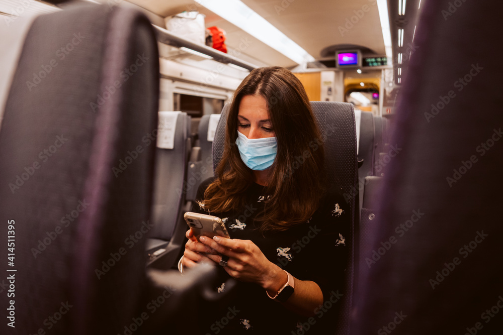 .Business woman traveling by train while the pandemic caused by covid 19. Using her smartphone to work. Social distancing