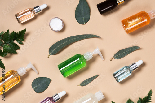 Many different natural cosmetic skincare bottle container or other cosmetic product on a beige background with eucalyptus leaves. Natural cosmetics from herbal ingredients.