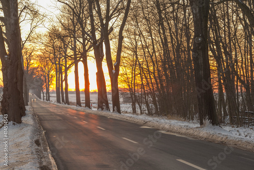 Zachód słońca nad asfaltową drogą.