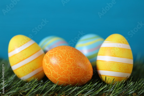 Easter holiday. striped easter eggs set on green grass on bright turquoise background..Spring festive easter background. copy space. Easter egg hunt