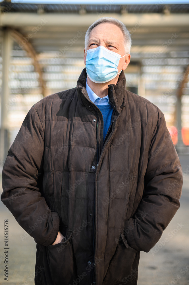 Senior man walking outdoor and wearing a protective mask against coronavirus pandemic