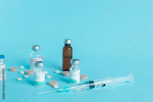 Medical ampoule, syringe and pills isolated on blue background