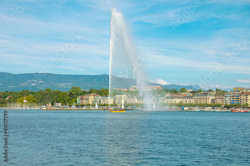 View of Jet d'eau fountain or water jet fountain, harbor and Geneva Lake. The most famous attraction and symbol of Geneva. Swiss Alps and skyline cityscape, on background. French Swiss Switzerland