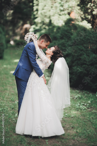 Newly married couple running and jumping in park while holding hands