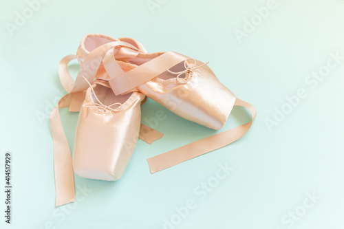 Valokuva New pastel beige ballet shoes with satin ribbon isolated on blue background